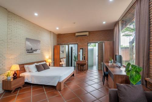 Ấp Thanh NguyênMekong Long Thanh Resort & Reststop的一间卧室配有一张床、一张书桌和一台电视
