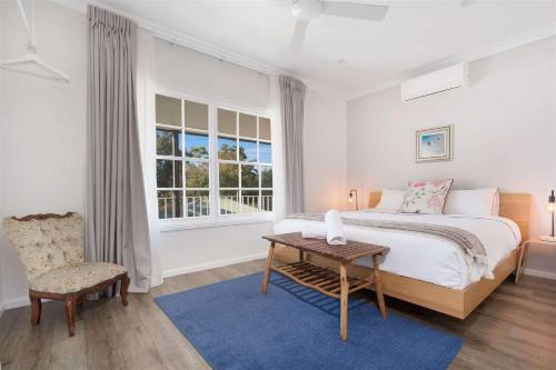袋鼠谷Myrtle Tree Lodge Leaves, Kangaroo Valley的卧室配有1张床、1张桌子和1把椅子