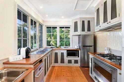 贝利雷菲尔德@贝瑞度假屋的厨房配有白色橱柜、木地板和窗户。