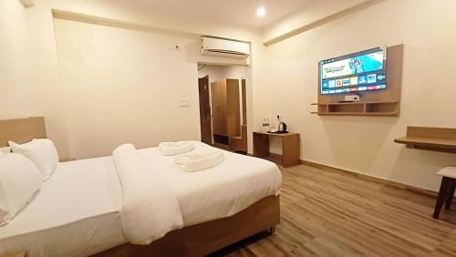 瑞诗凯诗Hotel Tapovanam Rishikesh的配有一张床和一台平面电视的酒店客房