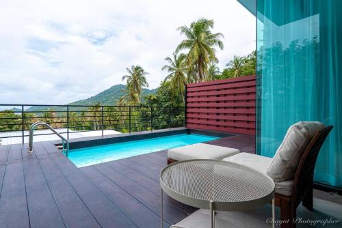 涛岛Matina Mountain Resort的阳台设有游泳池、桌子和椅子。