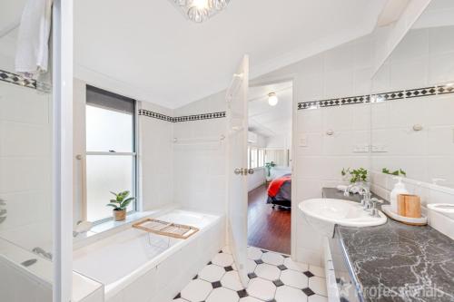 泽尔西Beachfront Holiday Cottage的白色的浴室设有浴缸和水槽。
