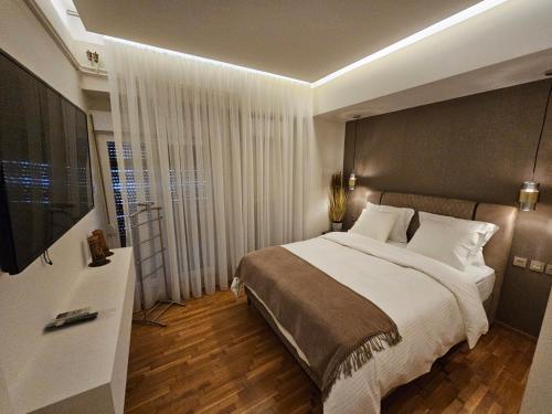 拉里萨Elektras Apartment στο κέντρο της Λάρισας με δωρεάν πάρκιγκ的一间卧室配有一张大床和电视