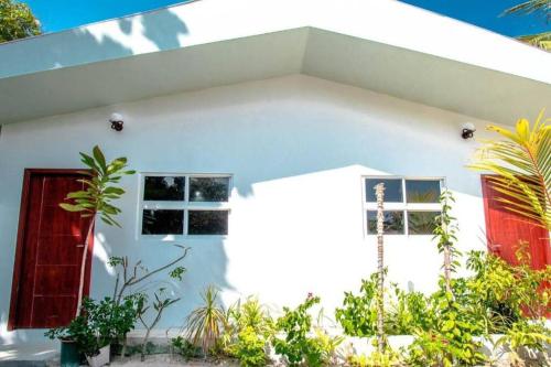 丹格迪Amore Apartment, Maldives的白色的房子,有红色的门和植物