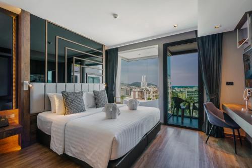 芭东海滩Rak Elegant Hotel Patong - SHA Extra Plus的一间带大床的卧室和一个阳台
