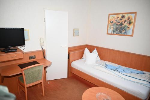 博尔库姆Hotel Passat的酒店客房配有一张床、一张书桌和一台电视。