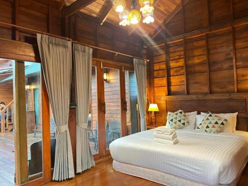 帕府Bann Rai I Na的卧室配有一张床铺,位于带木墙的房间内
