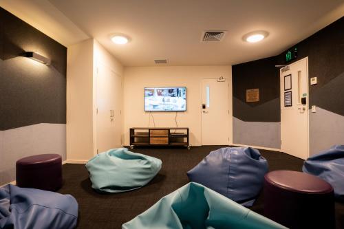 特卡波湖Haka House Lake Tekapo的一间设有蓝色椅子和平面电视的等候室