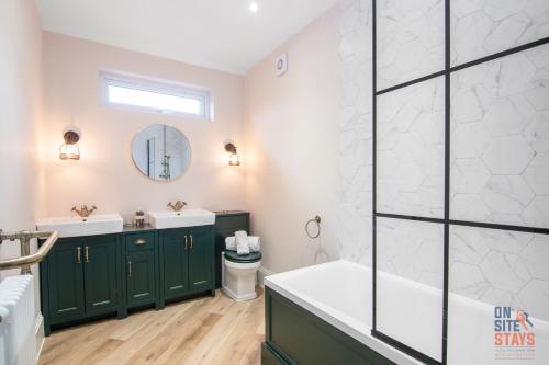 奥平顿OnSiteStays New Large modern 4 bed, Parking, Wifi, 2 x Bathroom的浴室设有绿色橱柜、浴缸和水槽。