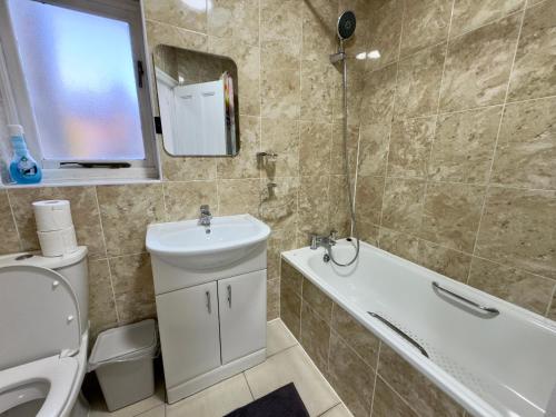 伦敦4 Bedrooms, 2 Bathrooms, Parking, Spacious House的浴室配有盥洗盆、卫生间和浴缸。