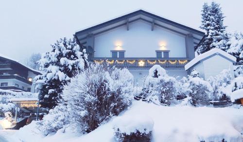 巴德小基希海姆Residence Alba Montis的雪覆盖着的房屋,里面装着灯