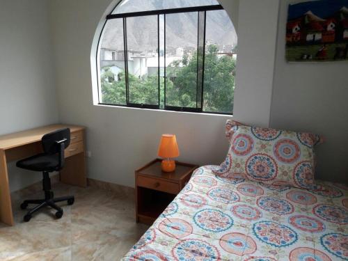 利马Terraza más habitaciones en La Molina的一间卧室配有一张床、一张书桌和一个窗户。