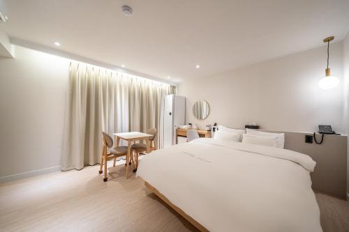 龟尾HOTEL SOHA的卧室配有一张白色的大床和一张桌子