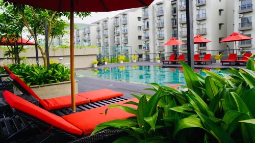 MalabeCoco Nest Colombo Sri Lanka的酒店游泳池设有红色椅子和遮阳伞