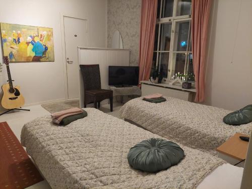瓦尔考斯Nostalginen residenssi Taika的一间卧室配有两张床、一台电视和吉他。