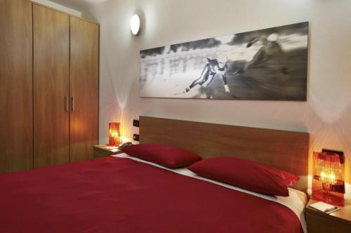 塞斯特雷Villaggio Olimpico Sestriere的一间卧室配有红色的床和两个红色枕头