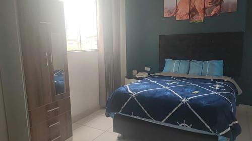特鲁希略HOSPEDAJE BLESS的一间卧室配有一张带蓝色棉被的床和窗户。