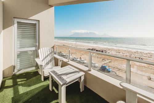 布鲁堡史特兰Voir la Mer - Blouberg Beach的阳台设有长凳,享有海滩美景。