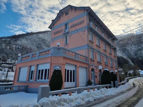 吕兹-圣索沃尔Appart Résidence Le Chili - Lit fait - Parc - Quartier thermal的一座粉红色的大建筑,四周有雪
