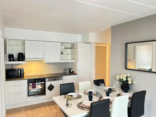 奥斯陆Luxurable super central 3 BR apt for a family of 6 in Oslo的白色的厨房设有餐桌和椅子