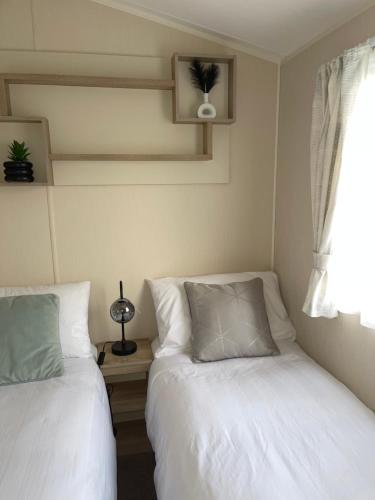 塔特舍尔Luxury Hot Tub Caravan Tattershall的一间卧室设有两张床和窗户。