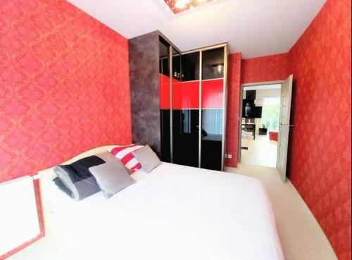 弗罗茨瓦夫ApartamentKosciuszki的卧室设有白色的床和红色的墙壁