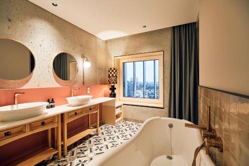 汉堡Villa Viva Hamburg的一间带两个盥洗盆、浴缸和窗户的浴室