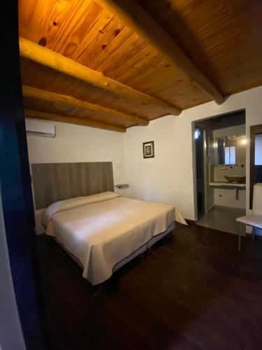 科隆Hotel Cristobal de Colón的卧室设有白色的床和木制天花板。