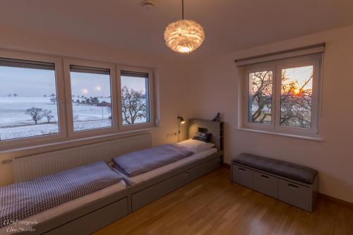 SimprechtshausenFerienhaus Taubenhof的一间卧室设有一张床和两个窗户。