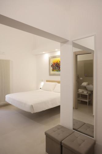 泰尔莫利Ruffini Rooms的白色卧室配有床和镜子