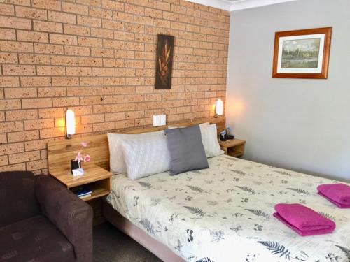 吉尔甘德拉三种方式汽车旅馆的一间卧室设有一张床和砖墙