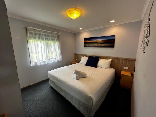 阿勒达拉Big4 Ulladulla Beachside Holiday Park的一间卧室配有一张带白色床罩的大床