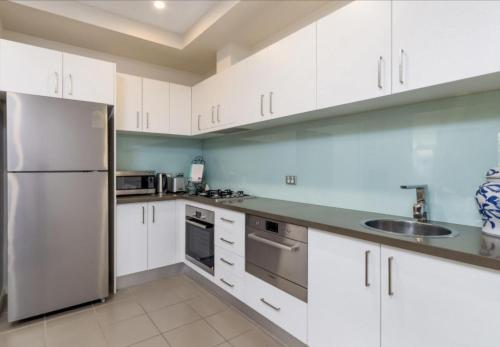 金斯顿Domain 27 Apartment - Barton的厨房配有白色橱柜和不锈钢冰箱