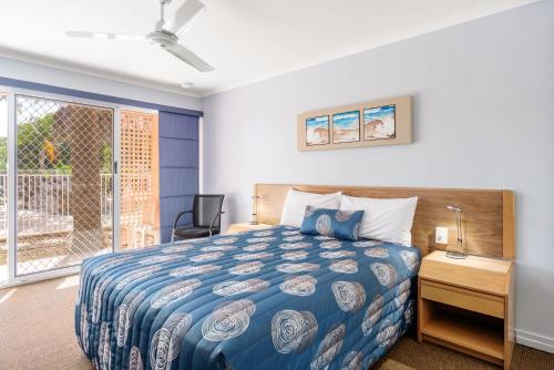 彩虹海滩Rainbow Sands Resort的一间卧室配有一张床、一张书桌和一个窗户。