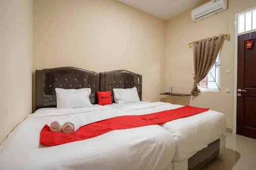 KedatonRedDoorz near UBL Lampung 2的卧室配有带红色枕头的大型白色床