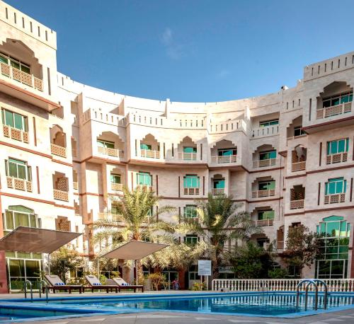 马斯喀特马斯喀特绿洲住处酒店的一座大型建筑,前面设有一个游泳池