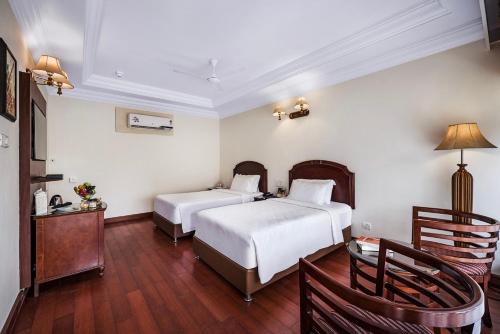 坦贾武尔GReaT Trails Riverview Thanjavur By GRT Hotels的一间卧室配有两张床和一张桌子及椅子
