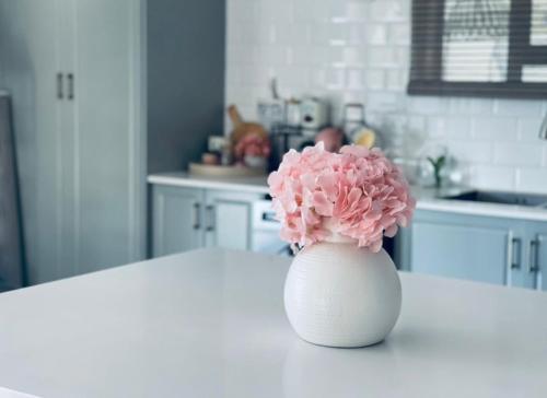马翁Luna Holiday Home的白色花瓶,花粉坐在桌子上