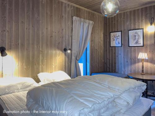 哈山Hafjelltunet的卧室配有白色的床和木墙