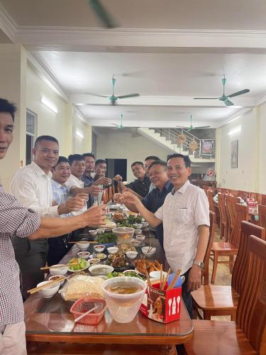 Tiên TânHotel Thi Hoa Bái Đính的一群男人站在桌子旁吃着食物