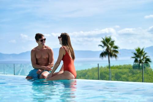 穆罗海滩Iberostar Selection Albufera Playa All Inclusive的坐在游泳池里的男人和女人