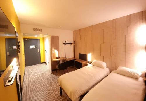 尼斯B&B HOTEL Nice Stade Riviera的酒店客房配有两张床和一张书桌