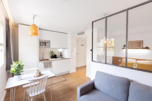 蒙彼利埃Les appartements de Montpellier的客厅以及带沙发和桌子的厨房。