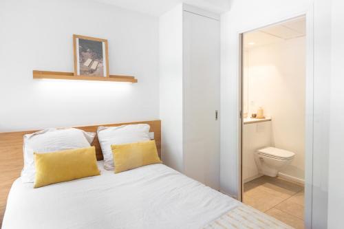 蒙彼利埃Les appartements de Montpellier的一间卧室配有一张带黄色枕头的床和卫生间