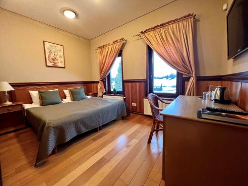 普列奈Harmony Park Countryside Villas & SPA的一间卧室配有一张床、一张书桌和两个窗户。