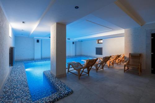 伊万诺-弗兰科夫斯克GANZ HOTEL的客房设有带椅子和桌子的游泳池。