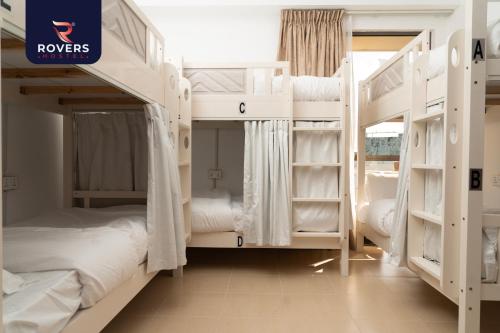 迪拜Rovers Hostel Dubai的一间设有两张双层床的客房,配有白色的双层床