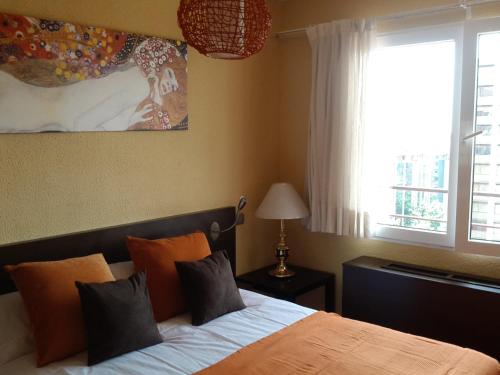 马德里卡勒马里西奥勒让德公寓的一间卧室配有带橙色枕头的床和窗户。