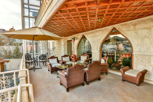 奥塔希萨尔Cappadocia Fairy Chimneys Minia Cave Hotel的庭院配有桌椅和遮阳伞。