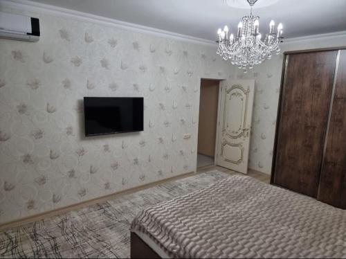 库萨雷Beautiful Villa的一间卧室配有一张床、一台电视和吊灯。